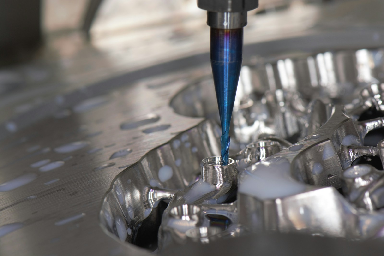 Close-up of a blue CNC cutting tool machining a precision metal component